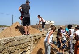 Volunteer Senegal Building volunteers shovel sand during the construction of a new classroom in Senegal.