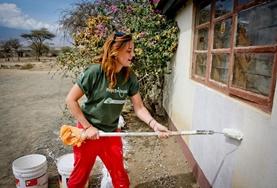 Volunteer Building A Building volunteer paints the wall of a completed school building at her placement in Tanzania.