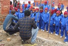 Volunteer Nepal Local children in Nepal look on excitedly while volunteers help with building classrooms for a school damaged during the 2015 earthquake.