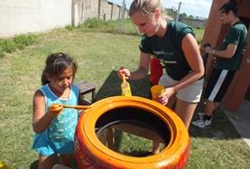 Volunteer Care A childcare volunteer and a local child work together to paint a tyre to be repurposed for a playground in Argentina.