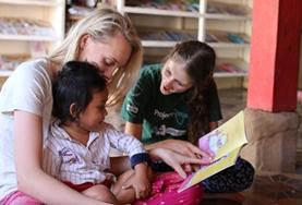 Volunteer Cambodia Two Care volunteers read to a child at a local daycare centre in Cambodia.