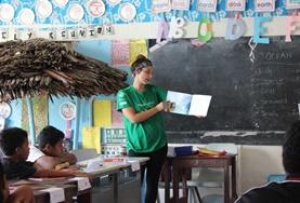 Volunteer Care A volunteer working with children reads an English book to her class in Samoa.