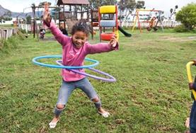 Volunteer Care A young child plays with hula hoops on a playground at our volunteer childcare placement in Cape Town, South Africa.