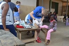 Volunteer Christmas A Medicine volunteer in Ghana assists with cleaning a child's wound during a healthcare outreach over the Christmas period.