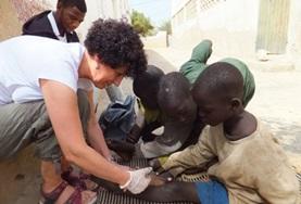 Volunteer Medicine & Healthcare A Nursing volunteer assists local medical staff with dressing children's wounds at our medical placement in Senegal.