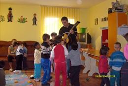 Volunteer Care A professional art therapist volunteering in Romania conducts a music therapy session with children at a care centre.