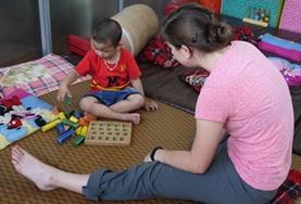 Volunteer Vietnam A qualified occupational therapist volunteer in Vietnam assesses a disabled child using a game that requires fine motor skills.