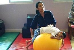 Volunteer Cambodia A qualified physiotherapist volunteer uses an exercise ball to treat a disabled child at a special needs centre in Cambodia.