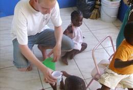 Volunteer Care A Care & Community volunteer gives a fresh glass of water to a young child at a childcare centre in Jamaica.