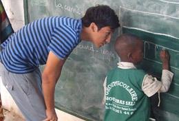 Volunteer Care A high school student teaches a child how to write on a blackboard at his volunteer placement at a school in Senegal.