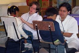 Volunteer Bolivia Two high school students measure children's heart rates during a volunteer Medicine outreach in Bolivia.