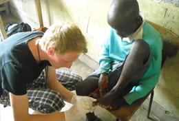Volunteer Kenya A high school student volunteering in Kenya helps with disinfecting a child's wound at a Medicine community outreach.