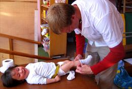 Volunteer Peru A high school student volunteering at our Medicine placement in Peru assists with dressing a baby.