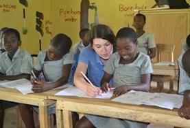 Volunteer Ghana A Teaching volunteer works with a school student in Ghana, helping her to complete an English language exercise during class.