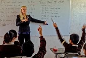 Volunteer Mexico School children raise their hands to answer a question asked by a Teaching volunteer giving a lesson at a school in Mexico.