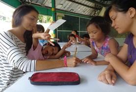 Volunteer Philippines A Teaching volunteer works closely with school students during an English language lesson at our placement in the Philippines.