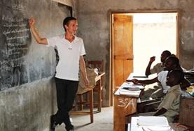 Volunteer Togo A Teaching volunteer demonstrates a lesson on a blackboard to a class of school students in Togo.